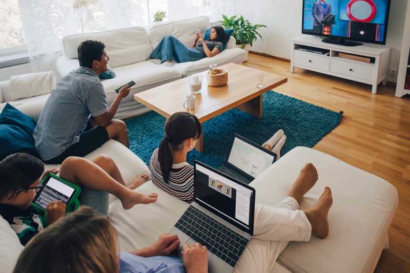 Familj som sitter i ett vardagsrum och kollar tv