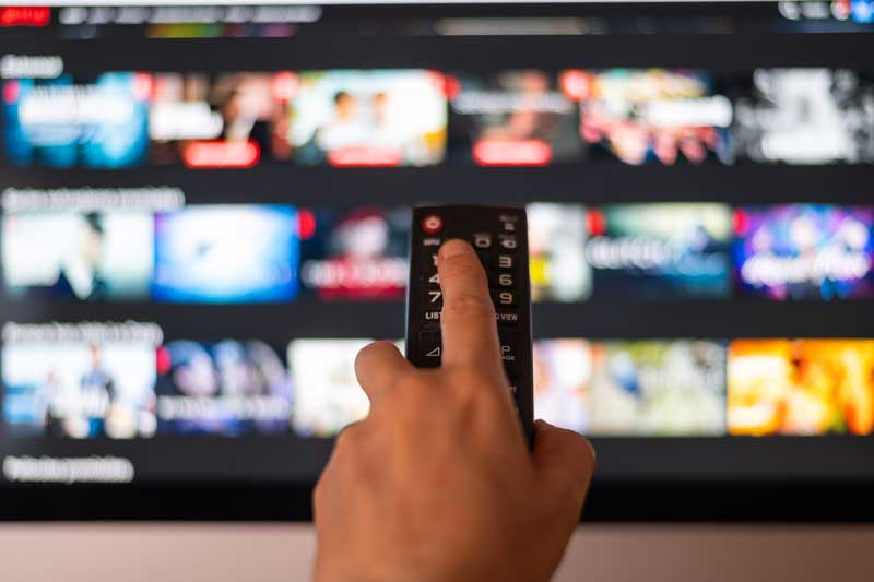 Hand håller i fjärrkontroll framför en TV
